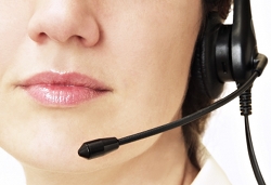 Nose-down shot of a telemarketer wearing a headset. Phone scams have been on the rise lately, especially in regards to domain names.